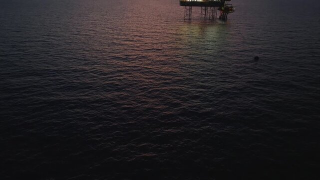 Aerial top view of offshore jack up rig and offshore platform during sunset for oil and gas exploration and production. 