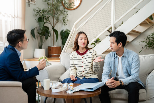 Young Asian couple sitting on sofa and talking with a professional therapist at clinic.Family therapy,Marriage,depression support,counselling,anxiety therapy,trauma advice,marriage help,mental health
