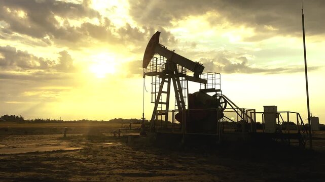 Oil extraction in oil field on sunset. Extraction of petroleum. Crude Oil Production. Crude pump jack working on oil field. Crude Pumpjack on sunrise. Industrial petroleum industry.