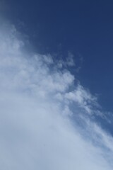 Obraz premium Clear blue sky with wispy white clouds above a calm open skyscape during daytime
