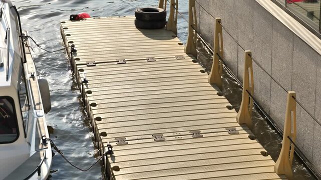 Plastic modular pontoon dock with a boat moored at a city river pier