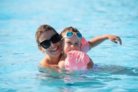 Happy Woman and Young Girl Having Fun in an Outdoor Swimming Pool