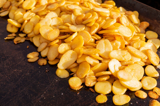 Golden Sliced Potatoes Cooking on a Dark Baking Tray