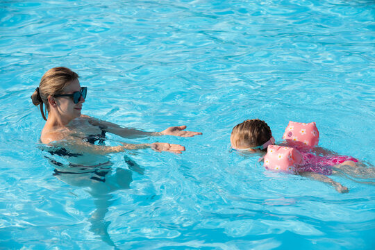 Happy Woman and Young Girl Having Fun in an Outdoor Swimming Pool