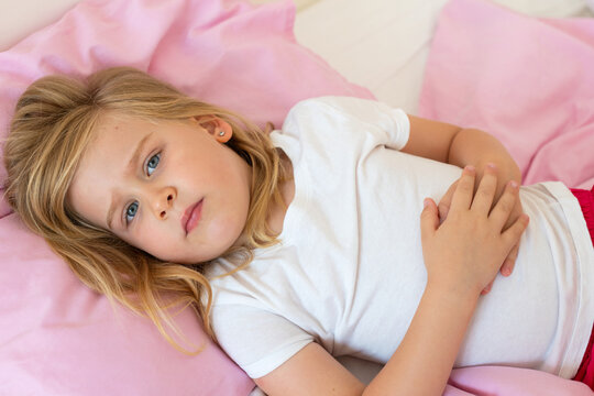Young Girl Suffering from Stomach Pain While Lying in Bed