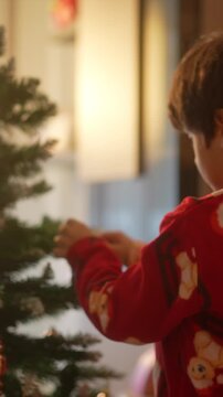 Little boy decorating the christmas tree at home