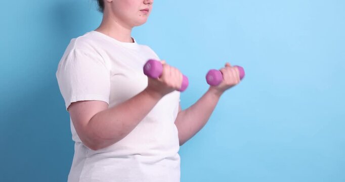 Weight loss. Overweight woman exercising with dumbbells on light blue background, closeup