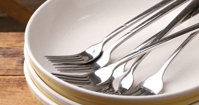 Ceramic dishware and forks on table, closeup. Camera moving right