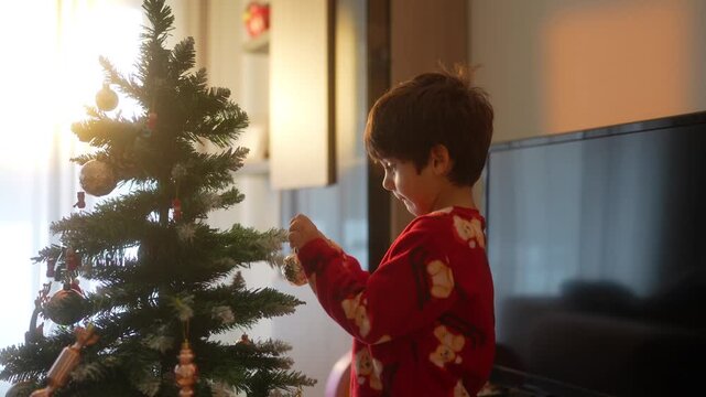 Little boy decorating christmas tree at home