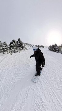 Person snowboarding down mountain slope in winter