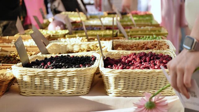 Market stall offering healthy dried berries and fruits in wicker baskets, promoting local food