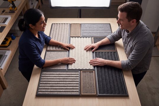 Two Interior Designers Collaborating and Examining Acoustic Wall Panel Samples on a Table in a Creative Studio Workshop