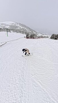 Woman snowboarding downhill on a snowy mountain slope