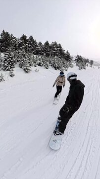 Romantic couple snowboarding together on mountain slope