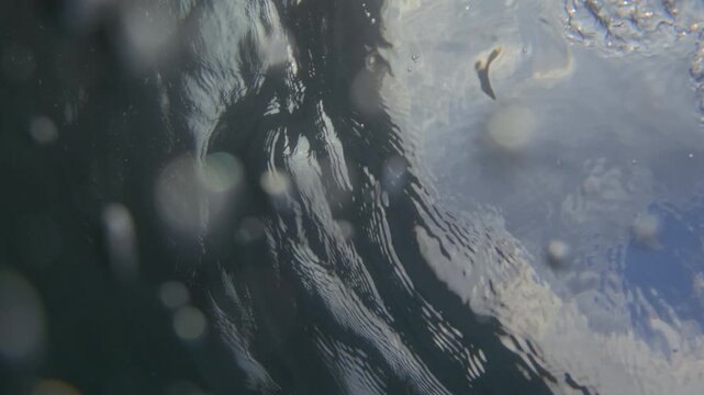 Underwater bubbles creating a motion effect in deep dark water with soft bokeh lights and liquid particles, abstract background
