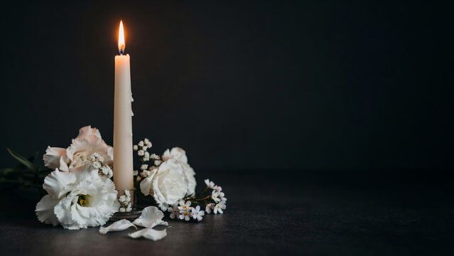 A solemn tribute with a lit candle and delicate white flowers, evoking remembrance and peace.