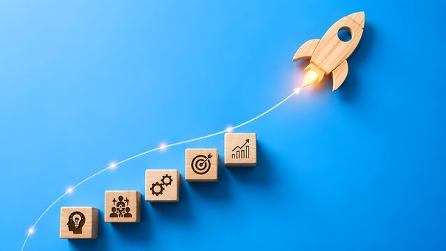 Wooden rocket launching above blocks with business strategy icons on blue background. Concept of startup growth and corporate innovation.