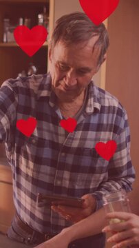 Animation of heart icons over caucasian father and daughter cooking