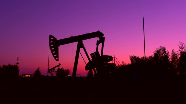 Oil extraction in oil field on evening sunset. Extraction of petroleum in night. Crude Oil Production. Crude pump jack working on oil field. Crude Pumpjack on sunrise. Industrial petroleum industry.