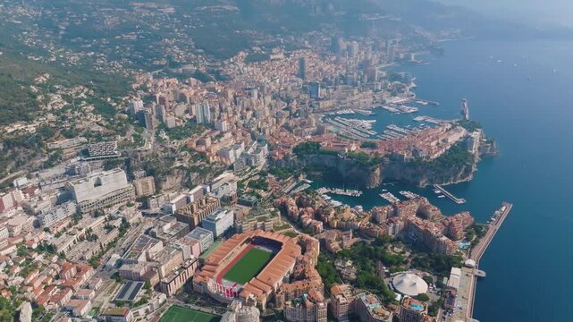 Monaco is captured from above, displaying its unique coastline and urban areas. The video shows the port, buildings, and residential spaces during midday. It highlights Monacos geographical features.