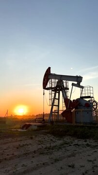 Oil extraction in oil field on sunset. Extraction of petroleum. Crude Oil Production. Crude pump jack working on oil field. Crude Pumpjack on sunrise. Industrial petroleum industry.