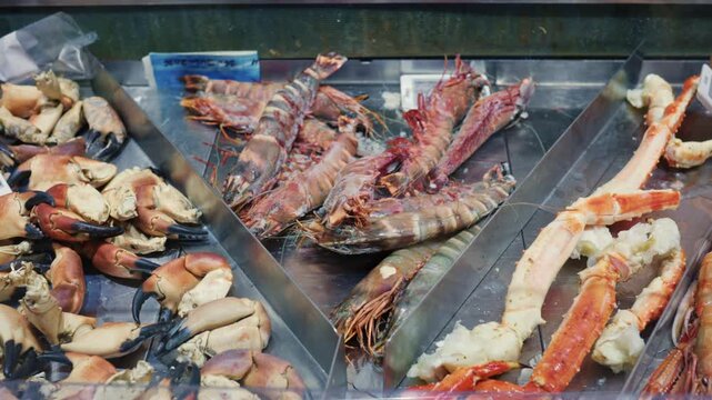 Fresh seafood prawns, crab claws, and crab legs arranged on a metal counter, ready for sale at a fish market