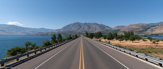 Obraz premium Straight forward‑reaching highway natural scenery, lake distant mountains blue sky white clouds, open countryside road for road trip travel 