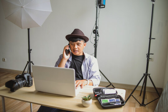 Freelancer Creator Talking on Smartphone Next to DSLR Camera and Lighting Gear