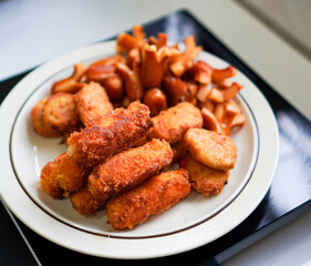 Fototapeta premium Right Side Angle Photograph of Homemade Fried Mozzarella Sticks, Chicken Nuggets and Mini Sausages on a Plate
