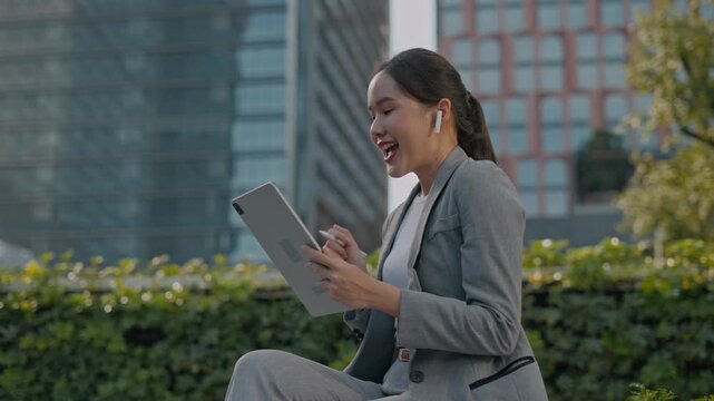 happy successful asian business woman using smartphone in front of modern business building.