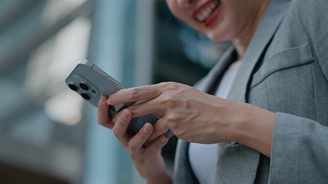 happy successful asian business woman using smartphone in front of modern business building.