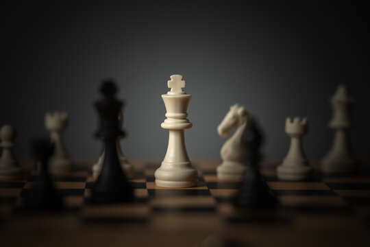 close-up of white chess king surrounded by blurred pieces on board