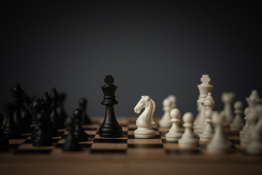 full chess set mid-game on wooden board, dark moody lighting