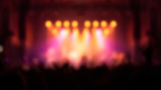 Blurry concert stage background with bright orange and pink ligh