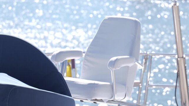 White marine helm chair on yacht deck with sunlit ocean bokeh