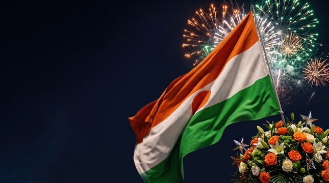 The national flag of niger waving against a dark night sky with colorful exploding fireworks and a decorative bouquet of orange and white flowers in the foreground
