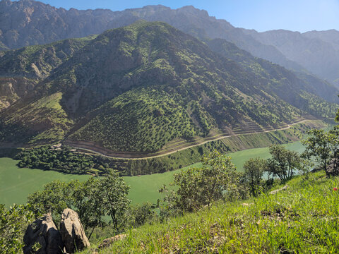 Winding emerald river carves through a mountain valley, framed by terraced green ridges and rugged alpine peaks under a bright sky.
📍 Hawraman Takht, Kurdistan, Iran 