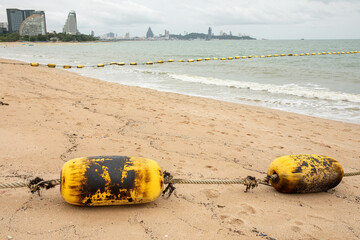 Two buoys covered in crude oil residue connected by rope on sandy beach, marine oil spill pollution and environmental disaster concept © seregraff