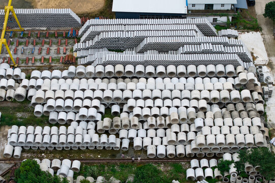 Aerial top‑down view of concrete pipe factory storage yard with industrial machinery