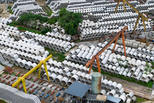 Aerial top‑down view of concrete pipe factory storage yard with industrial machinery