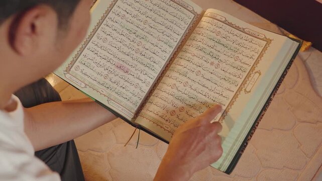 Close-up of a Muslim reading the Holy Quran and following Arabic verses with a finger in focused study. Islamic education, spiritual devotion, faith, worship, religious learning, and sacred scripture 