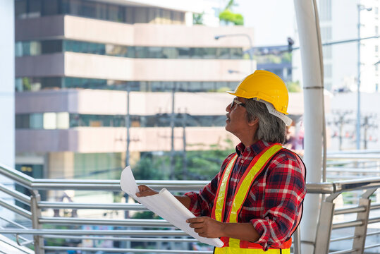 Confident Industrial Worker in Yellow Hardhat Teal Uniform Strong Professional Refinery Background
