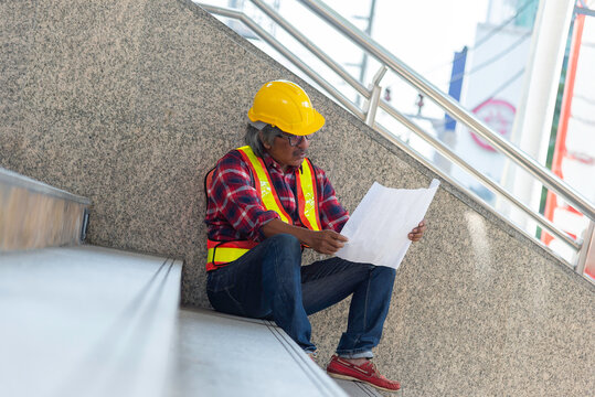 Confident Industrial Worker in Yellow Hardhat Teal Uniform Strong Professional Refinery Background