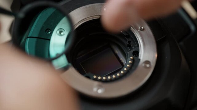 Close-up of tweezers lifting the IR cut filter out of a cinema camera, revealing the bare image sensor behind it. The key step of a full-spectrum camera modification &ndash; detailed sensor work.