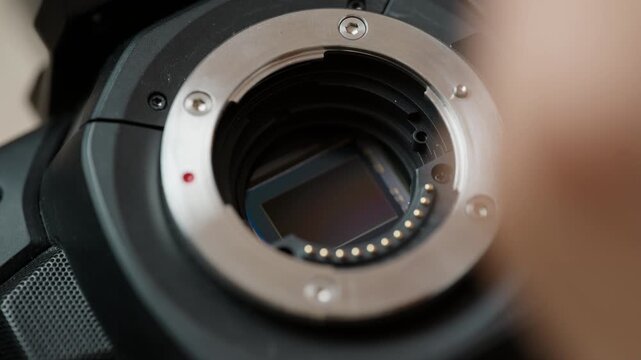 Close-up of tweezers placing a new IR cut filter onto the bare image sensor of a cinema camera. The rebuilding step of a camera modification &ndash; fitting fresh glass before closing the sensor stack.
