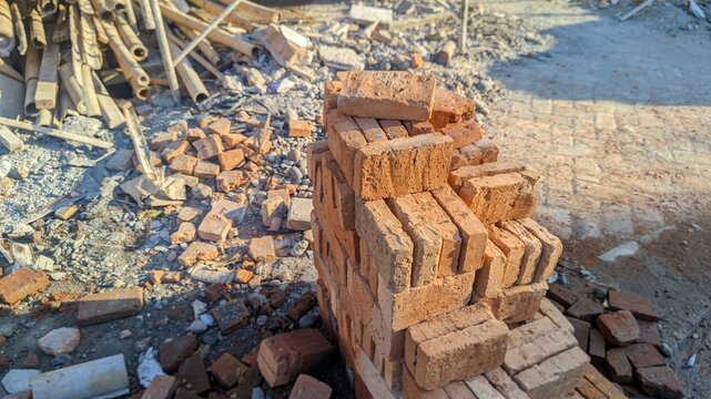 Stack of red bricks surrounded by rubble and debris at a construction or demolition site