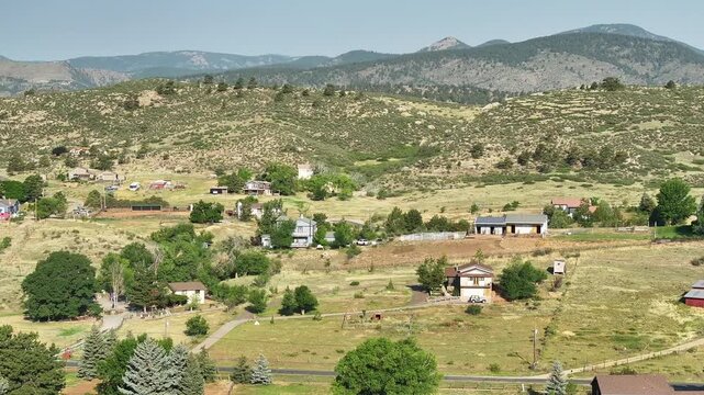 Scenic high-altitude vista showing the layout of country roads and rustic homesteads under a clear blue sky.