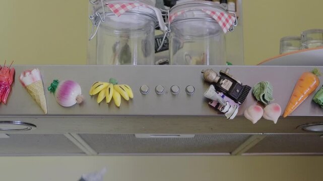 A hand uses a non-contact voltage tester to check an electrical outlet under a kitchen range hood. The tool beeps, indicating live current. Safety for home appliance installation.