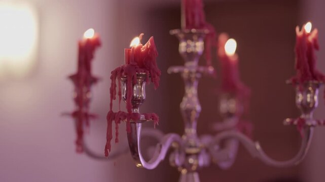 Burning red taper candles with dripping wax overflowing on silver candelabra arms