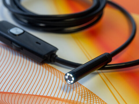 Close-up of a modern USB endoscope inspection camera with illuminated LED lights on a flexible black cable